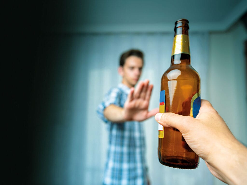 man with hand up saying no to a beer