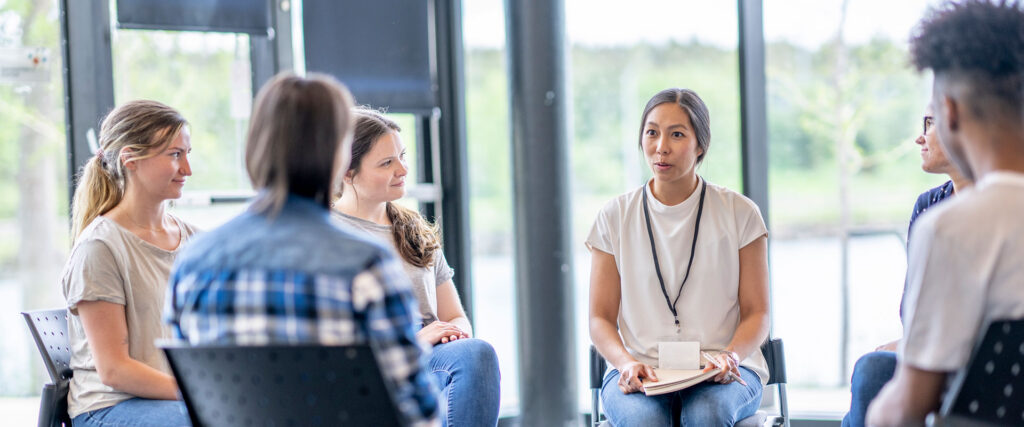 A diverse group of individuals engaged in conversation while seated in chairs, fostering a collaborative atmosphere.