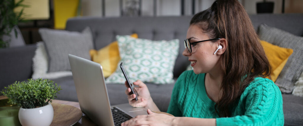 A woman in a green sweater sits on a couch, focused on her laptop, creating a cozy and productive atmosphere.